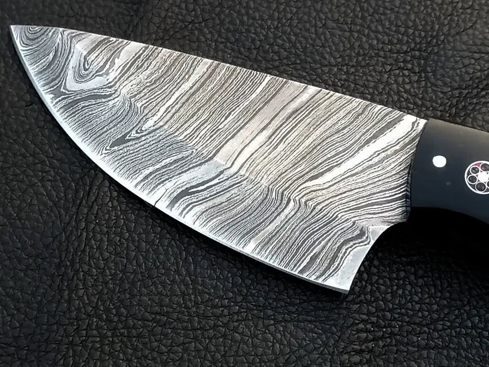Damascus Steel Skinning Knife-C94: black-handle knife on leather surface