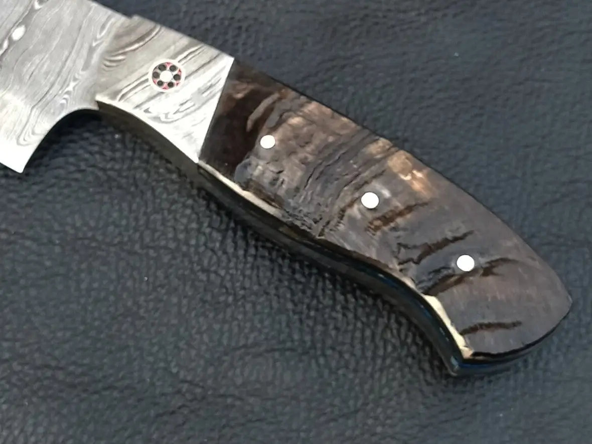 Damascus steel knife with black handle on black surface