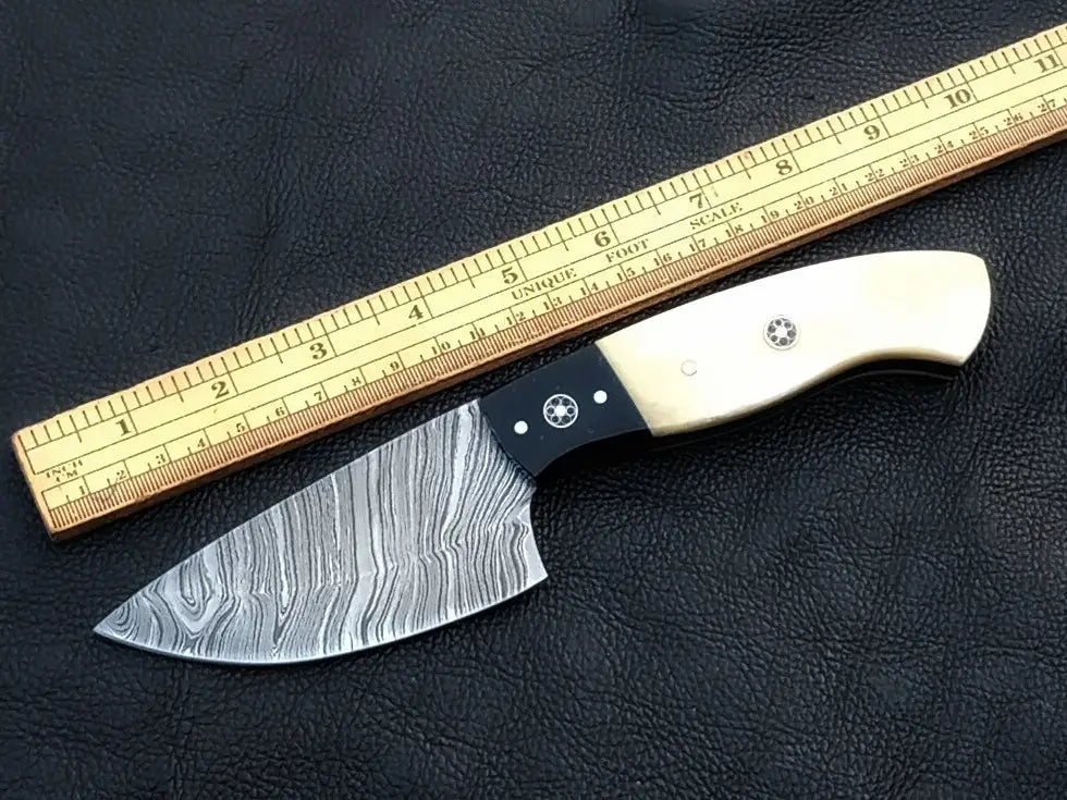 Damascus steel skinning knife with wooden handle on black leather surface