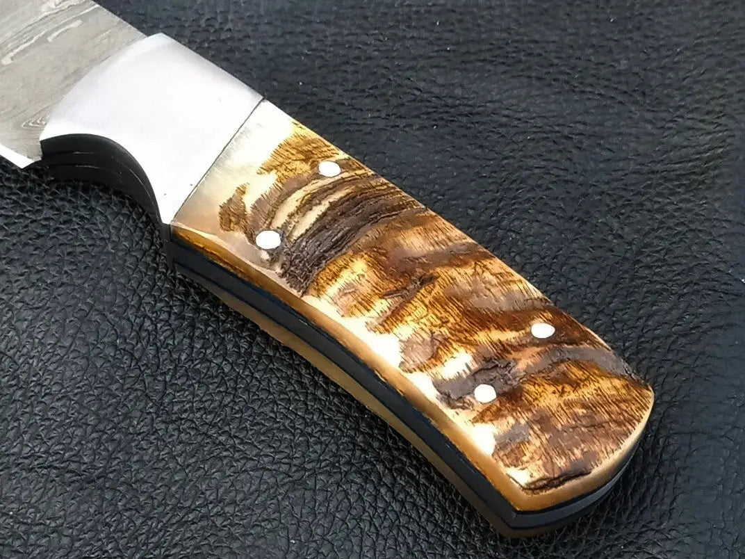 Handmade Damascus hunting knife with wooden handle on black surface