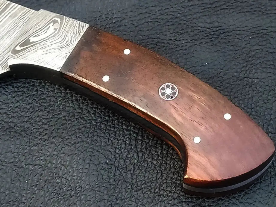 Handmade Damascus steel knife with wooden handle on black surface