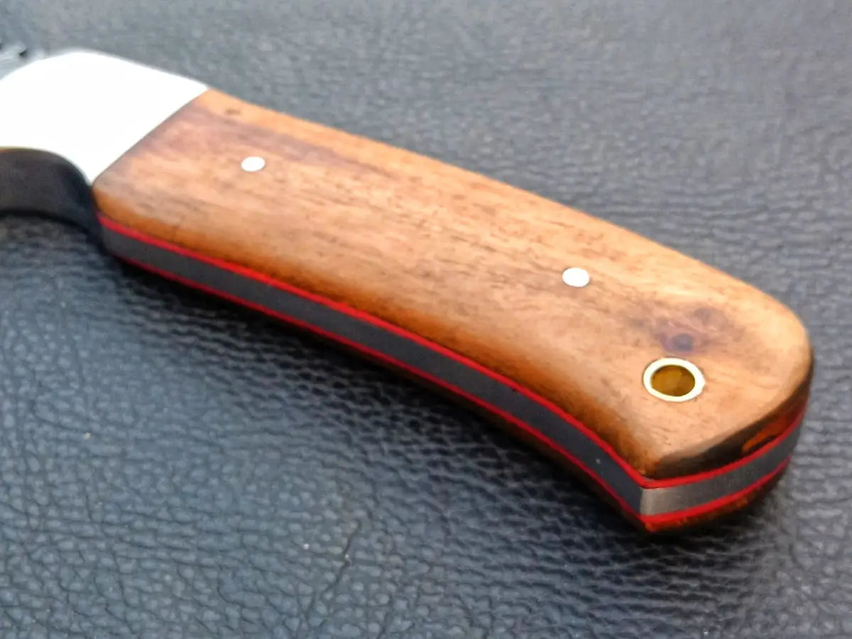 Handmade Damascus Steel Skinning Knife on black surface.