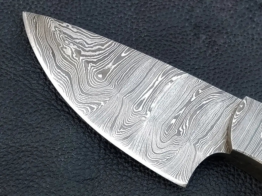 Damascus steel skinner knife on black surface